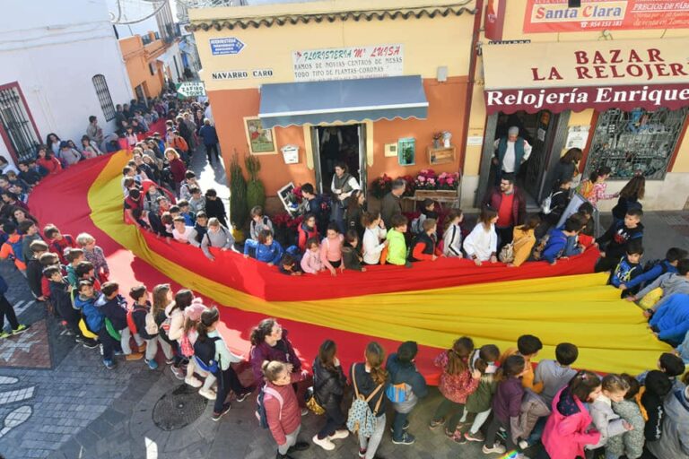 Tomares saca en procesión una bandera de España gigante portada por niños para celebrar el día de la Constitución
