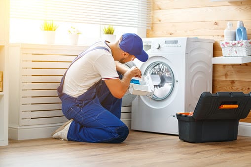 working man plumber repairs a washing machine in   laundry